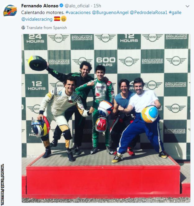 Fernando Alonso celebrates on a podium with fellow racing drivers