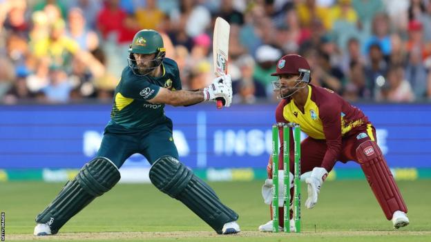 Australia batter Glenn Maxwell reverse slog sweeps a ball for six as West Indies wicketkeeper Nicholas Pooran watches on