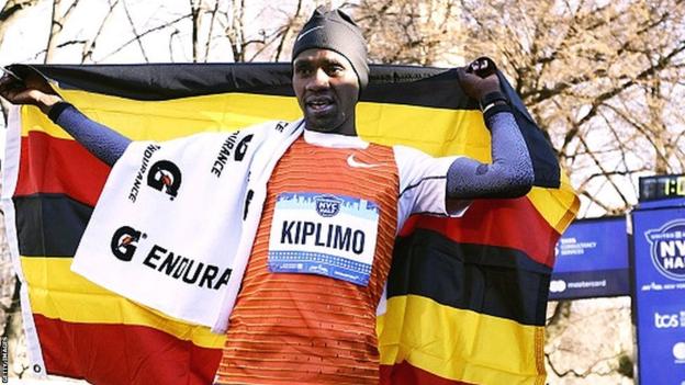 Jacob Kiplimo holds aloft a Ugandan flag after winning the 2023 NYC Half Marathon