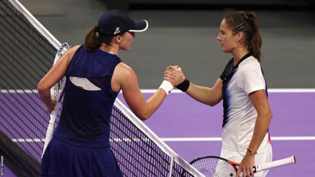 Iga Swiatek (left) shakes hands with Russian Daria Kasatkina (right) at the net after their match at the 2022 WTA Finals