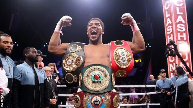 Anthony Joshua celebrates with his belts in the ring after beating Andy Ruiz Jr.