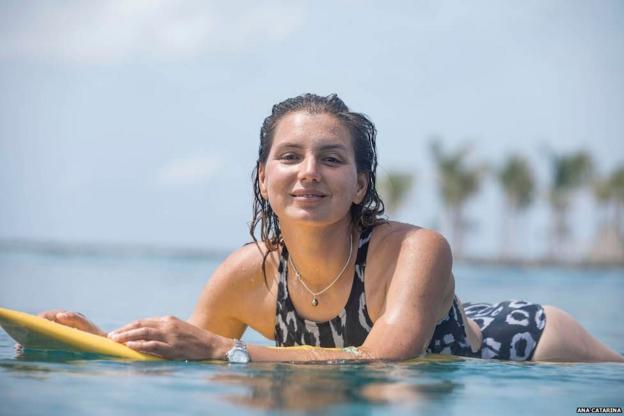 Maya Gabeira lächelt in die Kamera, während sie auf ihrem Brett schwebt