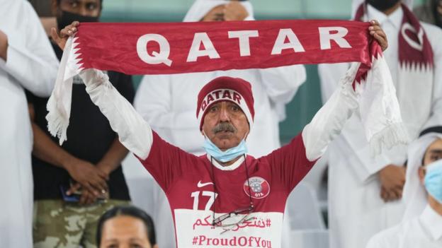 Fã segurando um cachecol de futebol do Qatar