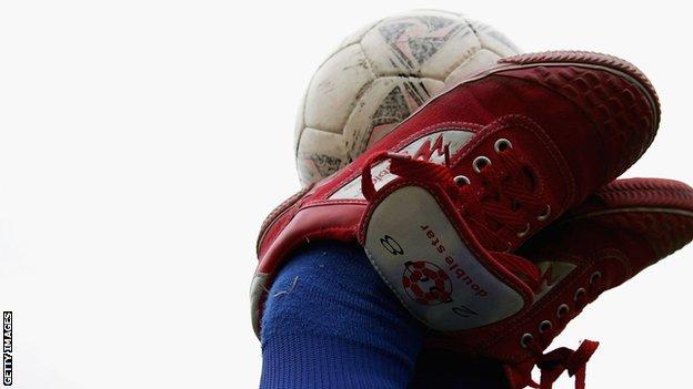 A child balances a football on his feet