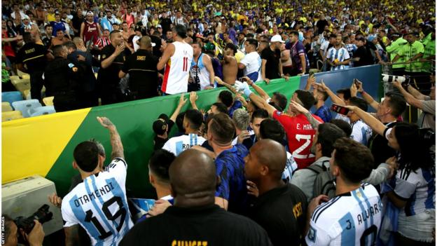 Argentina players crowded by the stand attempt to calm things down as police clash with fans
