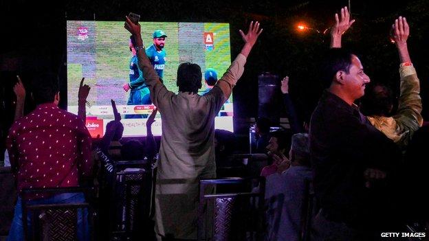 Cricket-fans ser direktesendt TV-sending på en storskjerm i Lahore