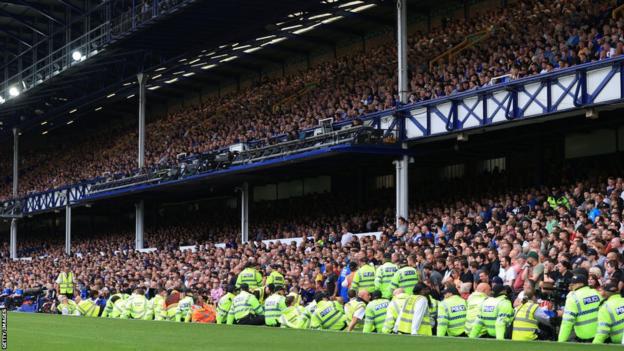 Police officers and stewards line the touchline during the last few minutes of the Premier League match between Everton FC and Liverpool FC