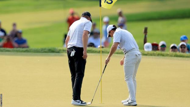 Michael Block and Rory McIlroy inspect the hole on the 15th green