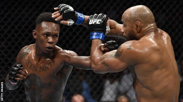 Israel Adesanya (left) punches Yoel Romero (right) during their middleweight fight at UFC 248
