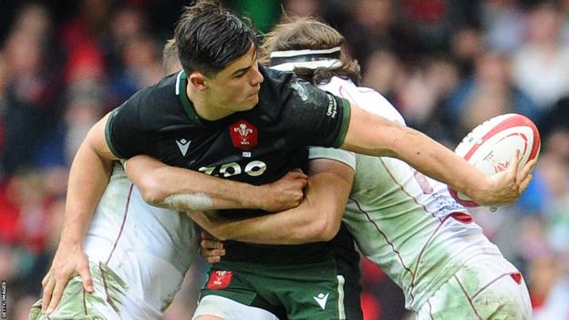 Louis Rees-Zammit flicks a pass out of a double tackle for Wales
