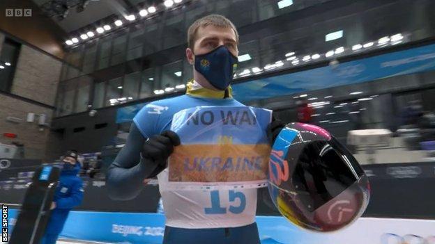 Vladyslav Heraskevych holding up a 'No war in Ukraine' sign