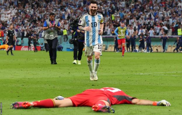Lionel Messi approaches a prostrate Emi Martinez after Argentina's penalty shoot-out win over the Netherlands at the 2022 World Cup