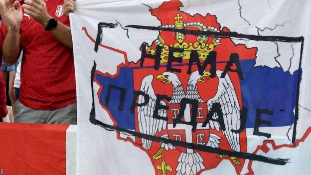 Serbian fans hold up a flag depicting the border of Kosovo with the flag of Serbia, with the words translated as 'do not surrender'