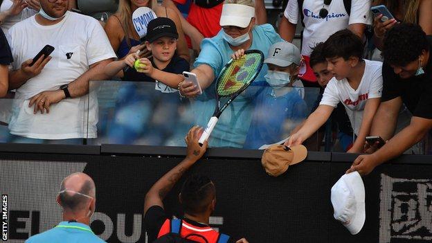 Nick Kyrgios gives a racquet to a boy he accidentally hit with a ball during the match