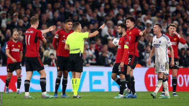 Manchester United players surround referee Donatas Rumsas in Copenhagen