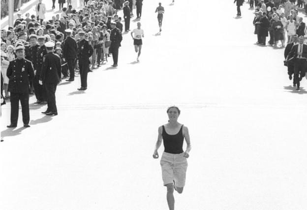 Bobbi Gibb runs alone with spectators watching her in the 1966 Boston Marathon