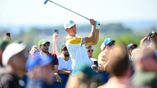 Ludiv Aberg hits a ball while being watched by fans at the Ryder Cup