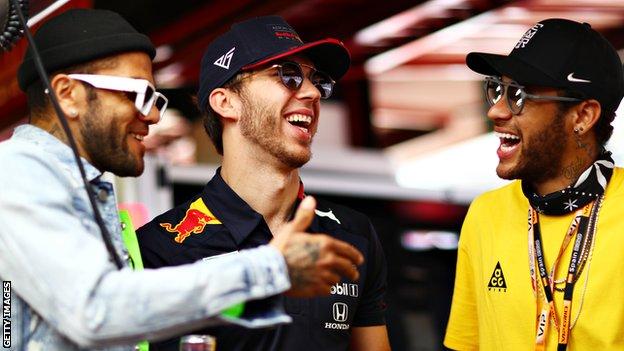 Red Bull Racing driver Pierre Gasly (centre) chats with footballers Dani Alves (left) and Neymar (right)
