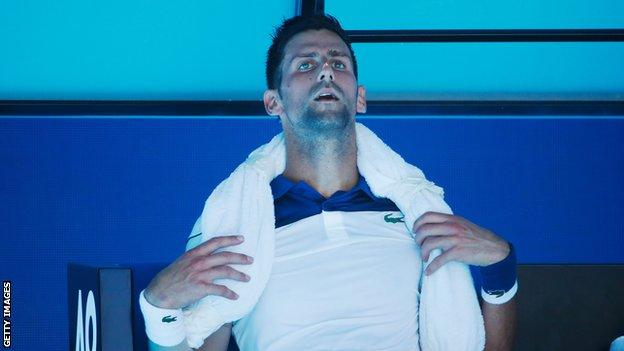 Novak Djokovic takes a break with an ice towel around his neck