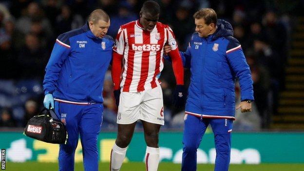 Kurt Zouma was led off at Turf Moor by head physiotherapist Dave Watson (left) and first team coach Eddie Niedzwiecki
