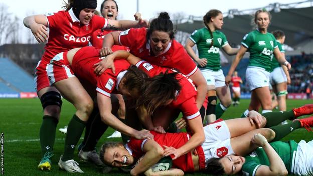 Hannah Jones of Wales is mobbed by team-mates after scoring try
