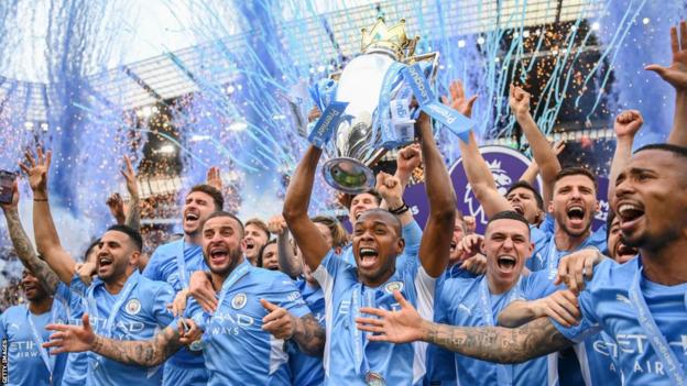 Fernandinho of Manchester City lifts the Premier League trophy with team mates Riyad Mahrez, Kyle Walker, Phil Foden, Kevin De Bruyne, Ruben Diaz and Gabriel Jesus