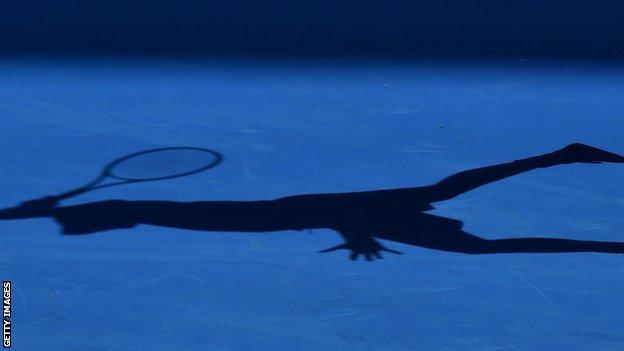 A tennis player casts a shadow
