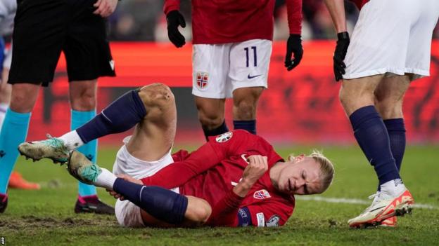 Erling Haaland holds his ankle while playing for Norway