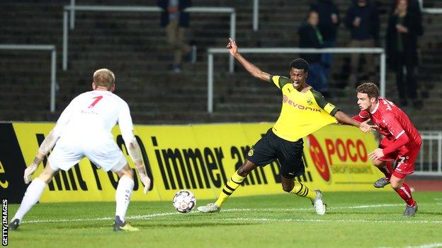 Alexander Isak is held back by a defender playing in front of a sparse crowd for Borussia Dortmund's reserves