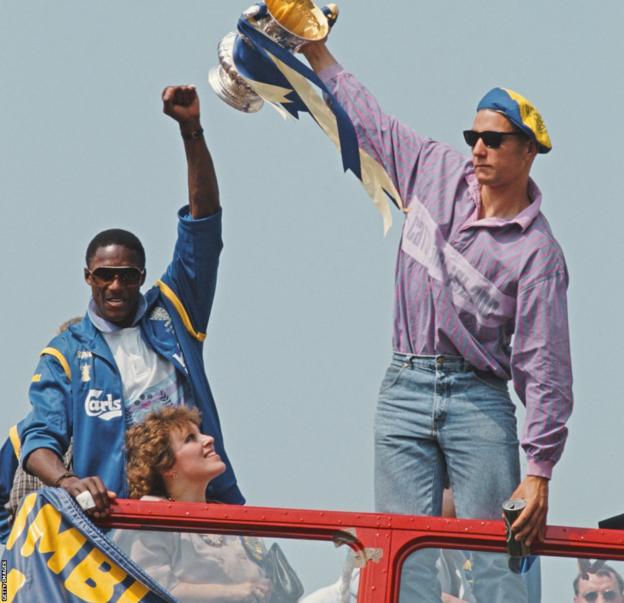 John Fashanu and Vinnie Jones lift the FA Cup on an open-top bus tour while Caroline Brouwer looks on