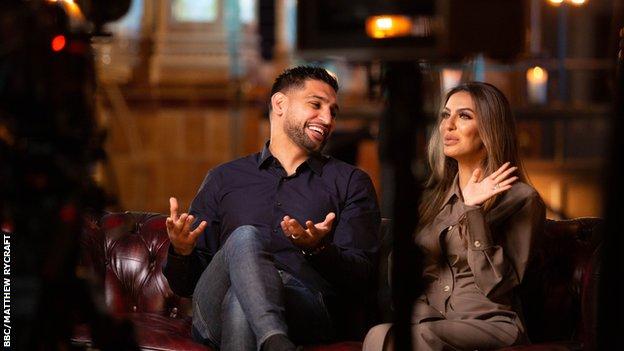 Amir Khan and Faryal Makhdoom being filmed on a sofa.