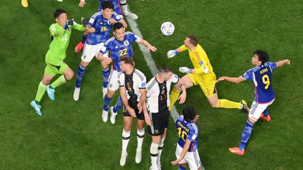 An aerial shot of Germany goalkeeper jumping for a header against Japan defender Maya Yoshida in a crowd of players from both teams