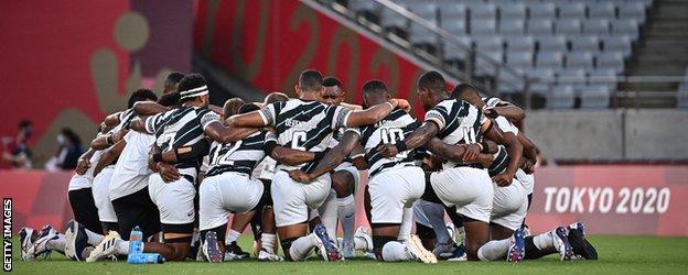 Fiji players kneel in a circle