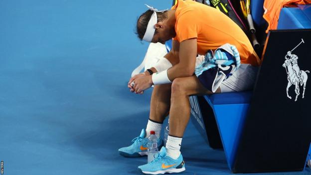 Rafael Nadal sits with his forearms resting connected  his knees, staring astatine  the ground