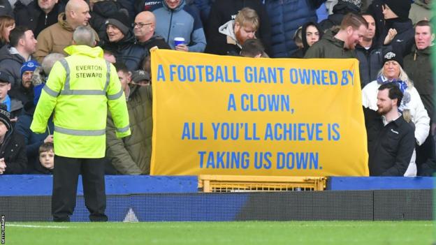Everton fans hold up a banner in protest against the club's owners
