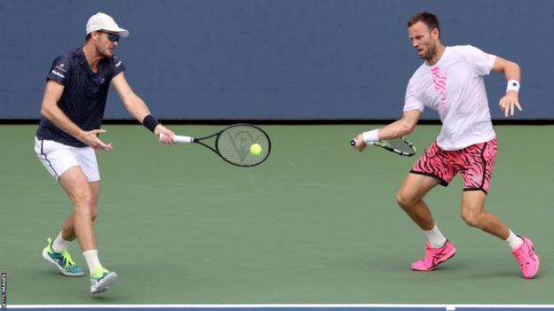Jamie Murray and Michael Venus both attempt to hit a tennis ball