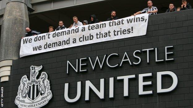 Newcastle fans unfurl a banner that reads "We don't demand a team that wins, we demand a club that tries!" after the takeoever was announced