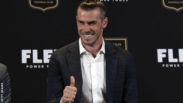 Gareth Bale smiles and gives a thumbs up as he addresses the media