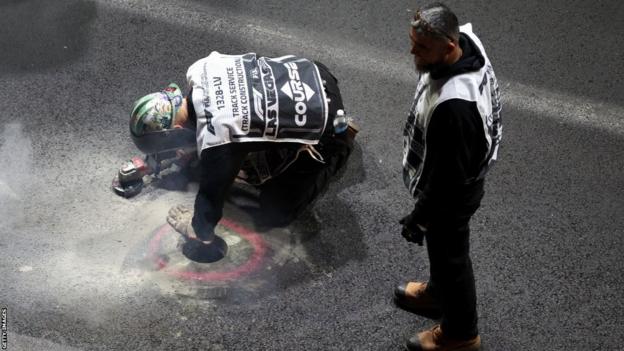 Track marshals and officials repair the man hole on the track