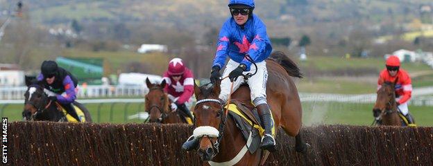 Horse 'Cue Card' ridden by Joe Tizzard (2R) jumps the last fence to win the Ryanair Steeple Chase during the third day of the Cheltenham horse racing festival in Gloucestershire, England on March 14, 2013