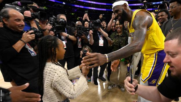 LeBron James hugs his daughter Zuri on the court