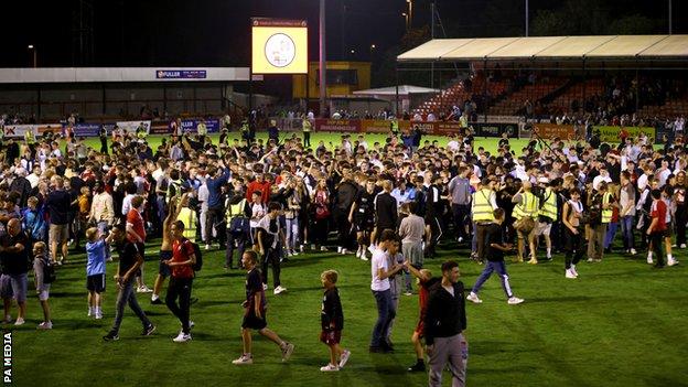 Crawley Town fans celebrate on the pitch at the end of the Carabao Cup second round match