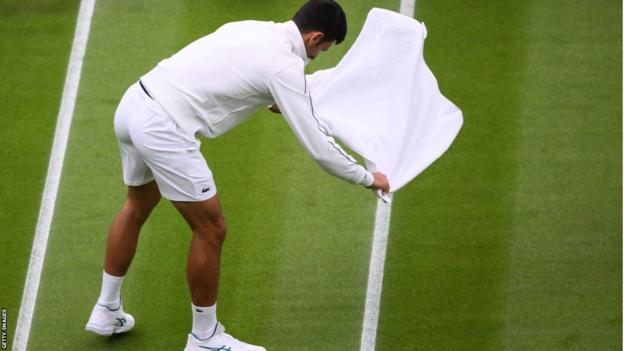 Novak Djokovic tries to adust  the court