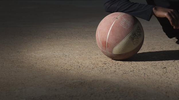 A girl rests her am on a basketball