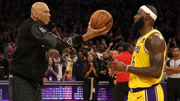 Kareem Abdul-Jabbar handing over the ball to Lebron James