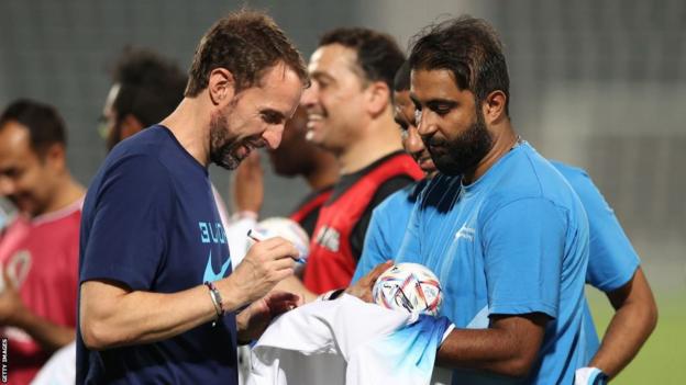 Gareth Southgate signs a shirt for a migrant worker