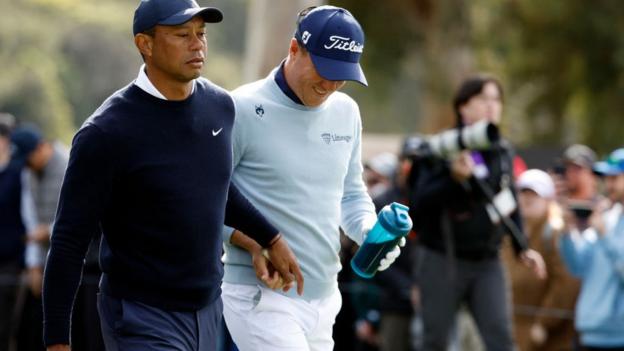 Se muestra a Tiger Woods entregándole un tampón a Justin Thomas mientras salían del noveno tee durante la primera ronda del Genesis Invitational.