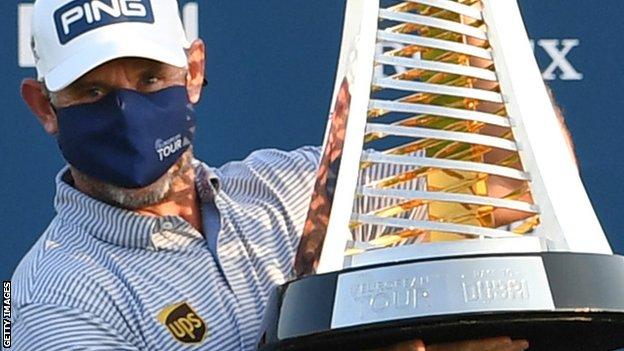 Lee Westwood in face mask with Race to Dubai trophy