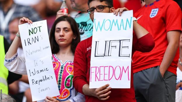 Two Iran fans holding up 'Women Life Freedom' banners