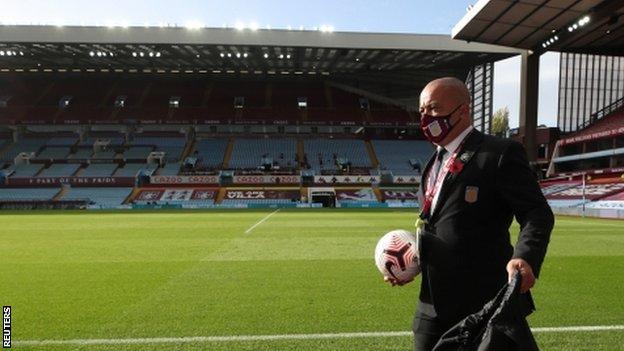 A member of Aston Villa's staff wearing a face mask before a game at Villa Park